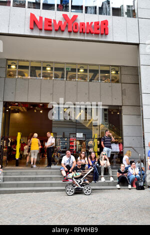 Außerhalb des "New Yorker" Kleidung Fashion Store im Zentrum der Prager Altstadt auf Na Prikope mit Besucher sitzen auf Schritte und Zeichen oben Stockfoto