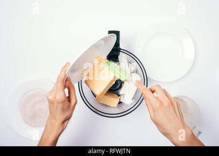 Blick von oben auf die Frau Hände hinzufügen Zutaten für den Teig in der Küchenmaschine neben Küchengeräte auf weißer Tisch. Stockfoto