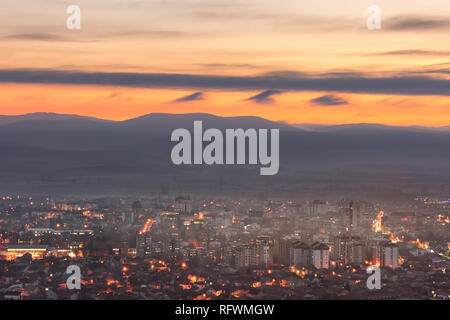 Unglaublich blaue Stunde Himmel über Pirot Stadtbild Aufhellen durch die Lichter der Stadt und nebligen Horizont Berge Stockfoto