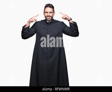 Junge christliche Priester über isolierte Hintergrund Lächeln zeigte mit beiden Händen, Finger, tolle Idee oder gedacht, gutes Gedächtnis zu Kopf Stockfoto