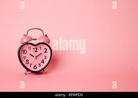 Wecker in Herzform auf rosa Hintergrund. Valentines Tag und Liebe und Dauer Konzept. Stockfoto