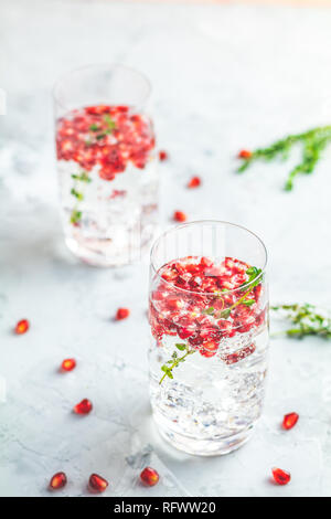 Festliche Getränke, Gin und Tonic Granatapfel Cocktail oder detox Wasser mit Eis. Selektiver Fokus, kopieren Platz für Text, Hellgrau konkrete Tischfläche. Stockfoto