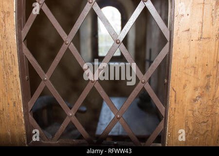 Der Blick durch ein Fenster mit einem eisernen Gitter auf uralten Gefängniszelle. Stockfoto