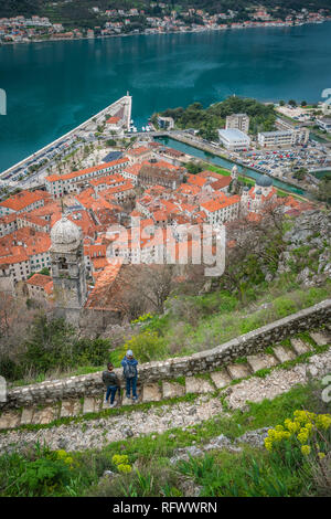 Kotor, Montenegro - April 2018: Zwei Touristen bewundern die Aussicht von der steinigen Trail und Schritte zur Festung oberhalb der Stadt Kotor Kotor Stockfoto