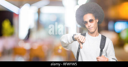 Junge afrikanische amerikanische Mann mit afro Haar mit Sonnenbrille und Rucksack mit Verärgerten Gesicht, negatives Vorzeichen zeigen Abneigung mit Daumen nach unten, Ablehnung c Stockfoto