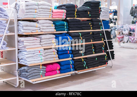 Ordentliche Stapel gefalteter Kleidung auf die Regale. Farbe Faltung shirt In einer durchorganisierten Clothing Store Stockfoto