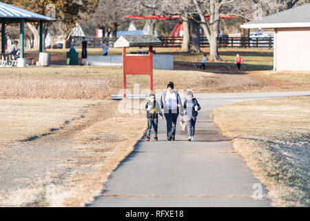 Reston, USA - 15. Februar 2018: Familie mit Mutter und Kinder zu Fuß auf dem Weg weg in der Nähe des Sees von Fairfax mit Spielplatz und die Menschen im Hintergrund, im V Stockfoto