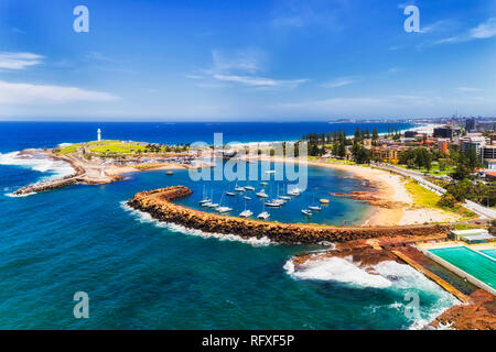 Geschützt Wollongong Stadt Hafen mit Marina und günstig Yachten hinter Sandstein wellenbrecher an der Wand und zwei weiße Leuchttürme mit Sandstrand in der Stadt Co Stockfoto