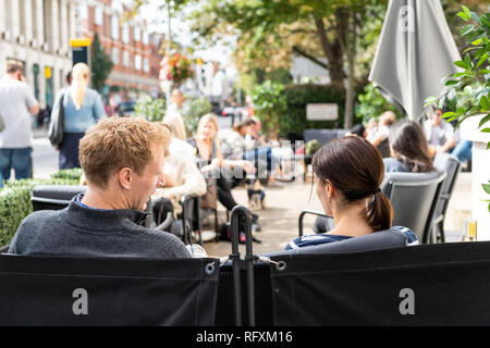 London, Großbritannien - 16 September 2018: Mann und Frau junges Paar draußen sitzen im Cafe Tabelle in Chelsea Restaurant im Freien Straße, Bürgersteig an der Joe und die Stockfoto