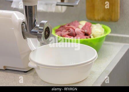 Weiß elektrischer Fleischwolf und Schüssel mit gehackten frischen Fleisches sind auf die Küche Stockfoto