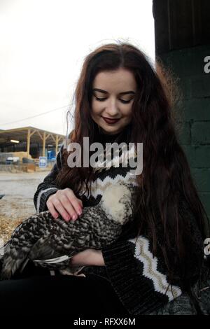 Langhaarige Mädchen auf einer Farm Knuddel eine flauschige Huhn Stockfoto