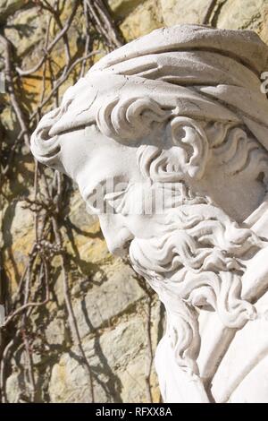 Nahaufnahme des Profils der Leiter der steinerne Statue eines alten Mannes mit langem lockigem Bart und einem Hut. Im Freien auf einer sehr sonnigen Tag. Stockfoto