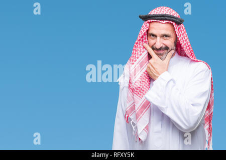 Senior arabischen Mann mit kufiya über isolierte Hintergrund in die Kamera schaut zuversichtlich mit Smile mit verschränkten Armen und Hand am Kinn angehoben. Thinki Stockfoto