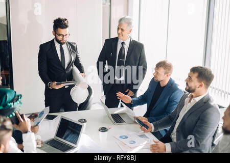 Männliche Manager machen Flipchart Präsentation auf diverse Kollegen an der Konferenz Stockfoto