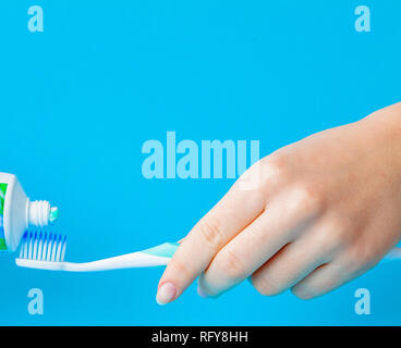 Zahnpasta auf eine Zahnbürste close-up auf einem blauen Hintergrund. Stockfoto