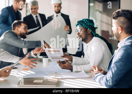 Multiethnische Gruppe von Bauherren und Architekten diskutieren Blueprint im Büro. Stockfoto