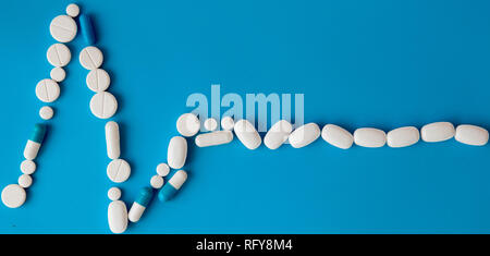 Arzneimittel weiße, runde herzförmige Pillen auf blauem Hintergrund isoliert. Tabletten in Form einer Linie des Herzrhythmus auf einem Pastell-blaue Hintergrund. Ca Stockfoto