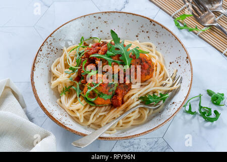 Spaghetti mit Thunfisch Kugeln in pikanter Tomatensauce und Rakete Stockfoto