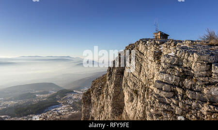 Sonnige felsige Gipfel mit Ruine an der Oberseite und sanften Landschaft und die Berge in der Ferne Schichten durch Nebel Stockfoto