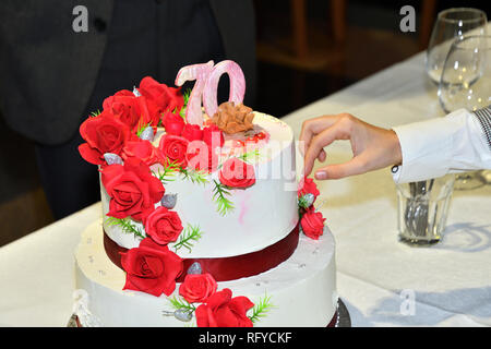 Kuchen Schneiden mit einem Messer zu 70 Geburtstage feiern. Stockfoto