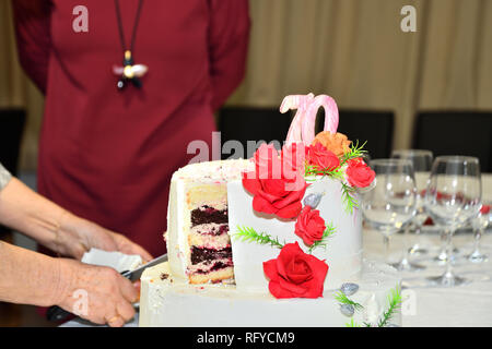 Kuchen Schneiden mit einem Messer zu 70 Geburtstage feiern. Stockfoto
