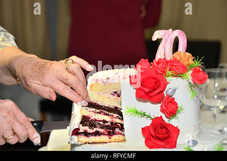 Kuchen Schneiden mit einem Messer zu 70 Geburtstage feiern. Stockfoto