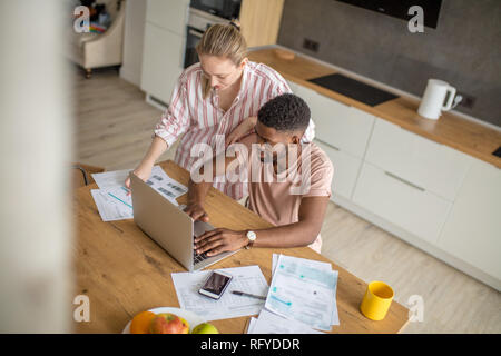 Junge interracial Paare mit Laptop zusammen frühstücken zu Hause Stockfoto