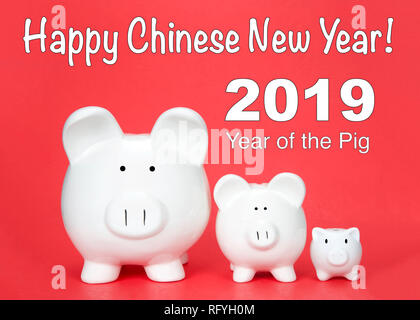 Frohes Chinesisches neues Jahr, das Jahr des Schweins mit drei Spardosen in verschiedenen Größen bis auf rotem Hintergrund gesäumt. Happy Chinese New Year text Stockfoto