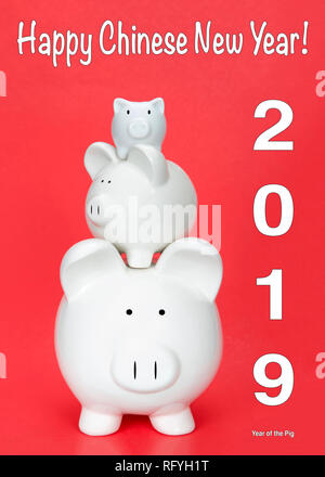Frohes Chinesisches neues Jahr, das Jahr des Schweins mit drei Spardosen in verschiedenen Größen aufeinander gestapelt auf roten Hintergrund. Happy Chinese New Year Stockfoto