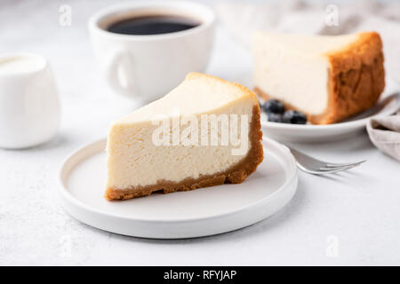 Käsekuchen New York mit Tasse Kaffee auf weißer Tisch. Detailansicht. Kaffeepause mit Kuchen und Kaffee schwarz Stockfoto