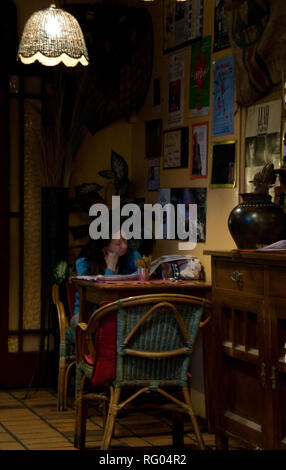 Eine Frau in einer dunklen Ecke ein Restaurant sitzen Stockfoto