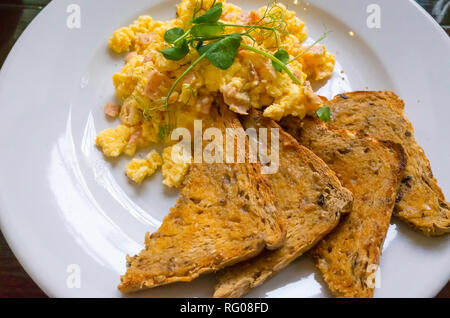 Frühstück, Brunch oder Mittagessen in einem Café Rührei mit Räucherlachs und multi Korn geröstetes Brot und Brunnenkresse garnieren Stockfoto