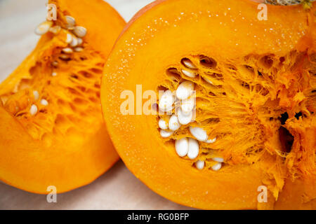 Leckere, gesunde und fleischigen Gemüse - saftig, hell orange Kürbis in einem Schnitt mit Samen in Nahaufnahme, neben einem Schneiden Schneiden. Kürbis oval mit einer harten Kruste geprägt. Stockfoto