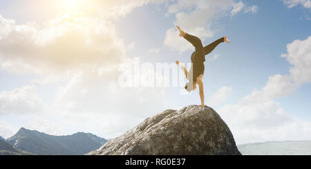 Erstaunlich yoga Mann sie einen Handstand auf Rock. Mixed Media Stockfoto