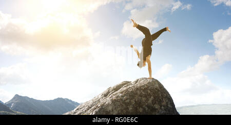 Erstaunlich yoga Mann sie einen Handstand auf Rock. Mixed Media Stockfoto