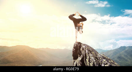 Erstaunlich yoga Mann sie einen Handstand auf Rock. Mixed Media Stockfoto