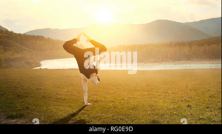 Erstaunlich yoga Mann sie einen Handstand outdoor. Mixed Media Stockfoto