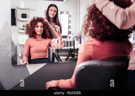 Nette junge Frau, die ihr Haar berühren Stockfoto