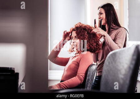 Nette gut aussehende Frau ihr Haar zur Festsetzung Stockfoto