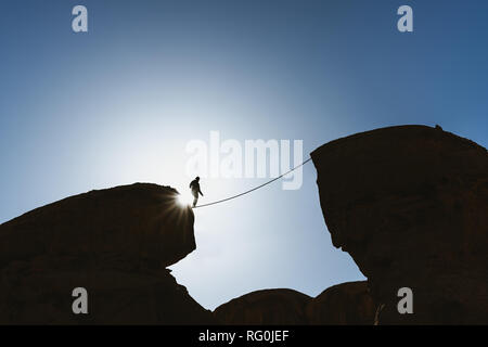 Ein Mann Balancing zu Fuß auf Seil über Abgrund. Business, Risikobereitschaft, Herausforderung, Mut und Konzentration Stockfoto