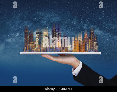 Immobilien Unternehmen, intelligente Stadt und Gebäudetechnik. Geschäftsmann Hand digital Tablet mit Gebäuden Hologramm und Sterne Hintergrund Stockfoto