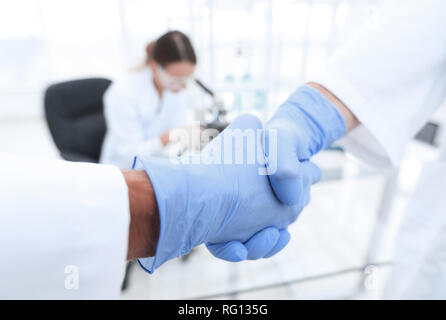 Hand in den medizinischen Handschuh (Handshake). Stockfoto