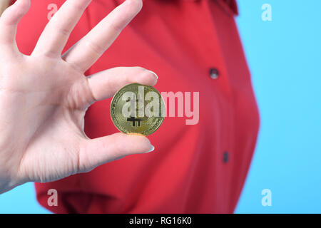 Pretty Woman holding Neue Goldene cryptocurrency Bitcoin in Händen auf blauem Hintergrund Stockfoto