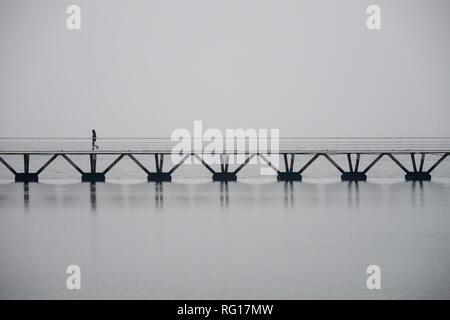 Einsamer Mann auf einer Brücke über Wasser in Lissabon, neblige Atmosphäre, Copyspace Stockfoto