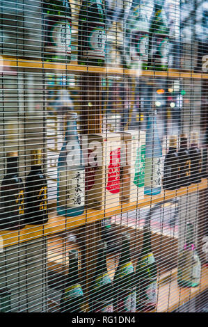 Sake Flaschen im Fenster einer Bar & Restaurant in Shoreditch, Central London. London Sake Bar. Stockfoto