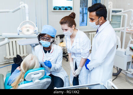 Gesundheit und Gesundheitswesen. Eine multinationale Gruppe Zahnärzte untersucht Röntgenstrahlen in der Gegenwart eines Patienten. Praxis an einer medizinischen Universität. Stockfoto