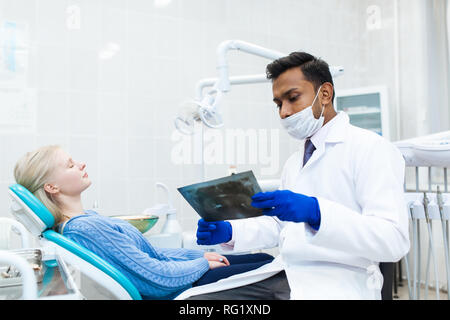 Männliche asiatischen Zahnarzt in der Zahnarztpraxis im Gespräch mit weiblichen Patienten und Vorbereitung der Behandlung. Moderne medizinische Ausrüstung Stockfoto