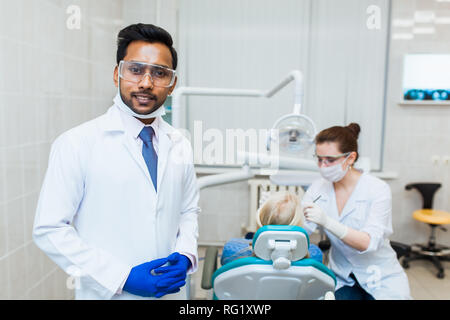 Männliche asiatischen Zahnarzt in der Zahnarztpraxis im Gespräch mit weiblichen Patienten und Vorbereitung der Behandlung. Moderne medizinische Ausrüstung Stockfoto