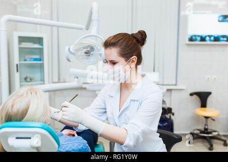 Weibliche Zahnarzt in der Zahnarztpraxis im Gespräch mit weiblichen Patienten und Vorbereitung der Behandlung. Moderne medizinische Ausrüstung Stockfoto