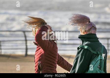 Blackpool, Lancashire. 27 Jan, 2019. UK Wetter. Gale force Winde an der Küste. Die Besucher der Stadt am Meer haben strenge Winde mit Fußgängern auf der Strandpromenade ausgeblasen wird zu ertragen. Sturm, Schlag, tempest, Flyaway Haar, verwirrte Tresses, Bad Hair Day auf der Strandpromenade. Credit: MediaWorldImages/AlamyLiveNews Stockfoto